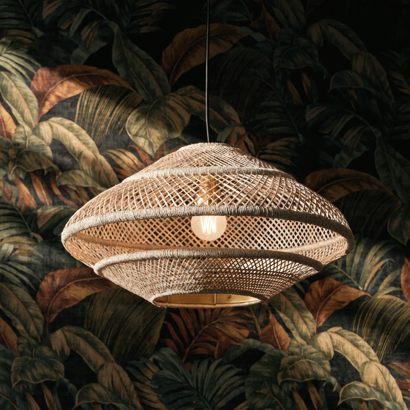 Luminária de fibra natural iluminada sobre papel de parede botânico